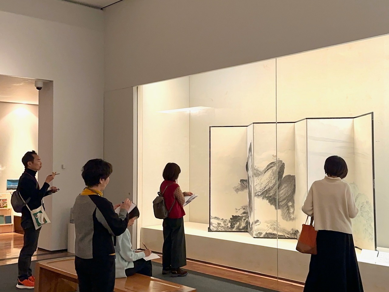 屏風作品の前で参加者が手元のボードを俳句をつくっている