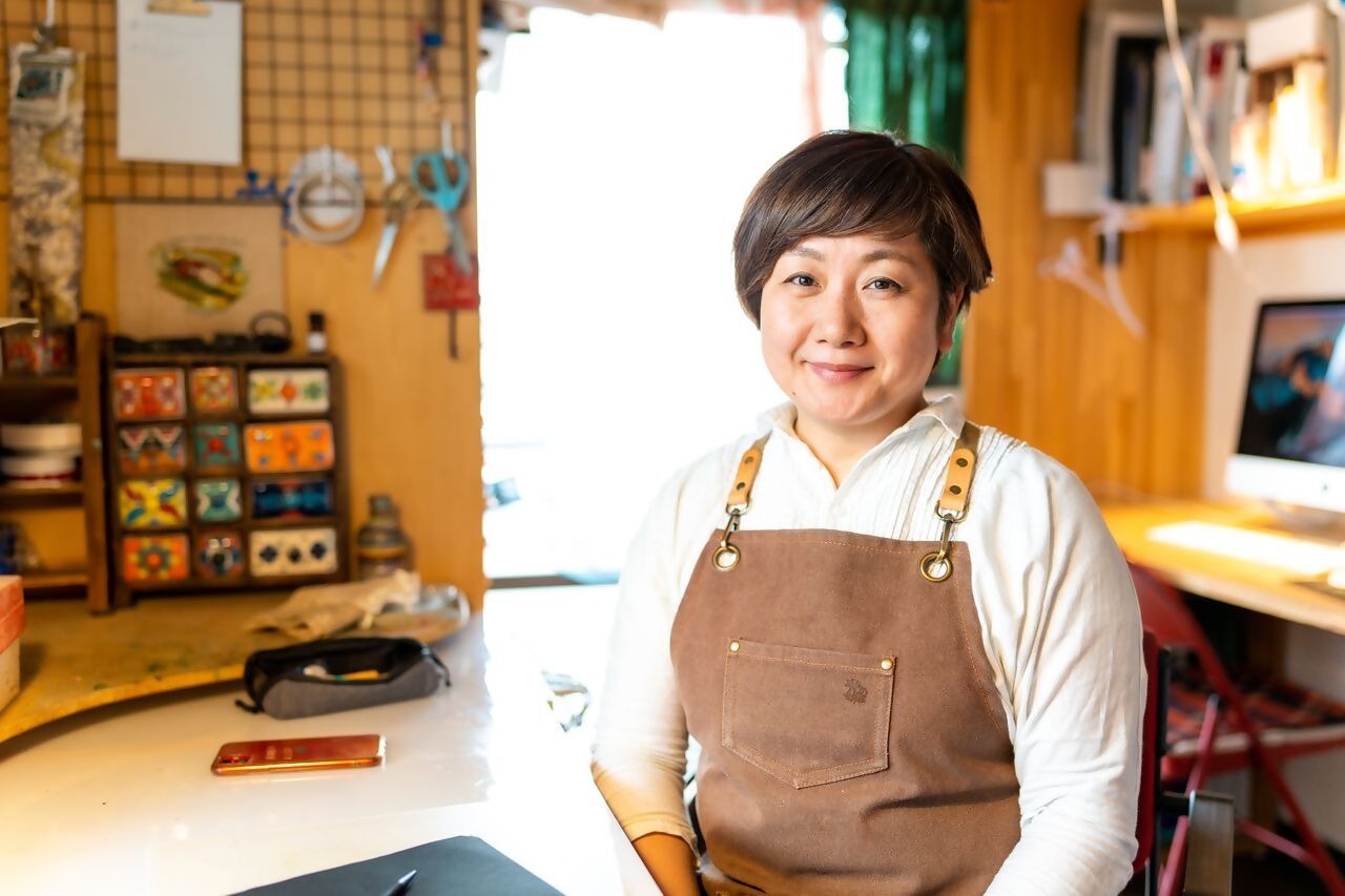 エプロンをつけて座っている酒井敦美さん
