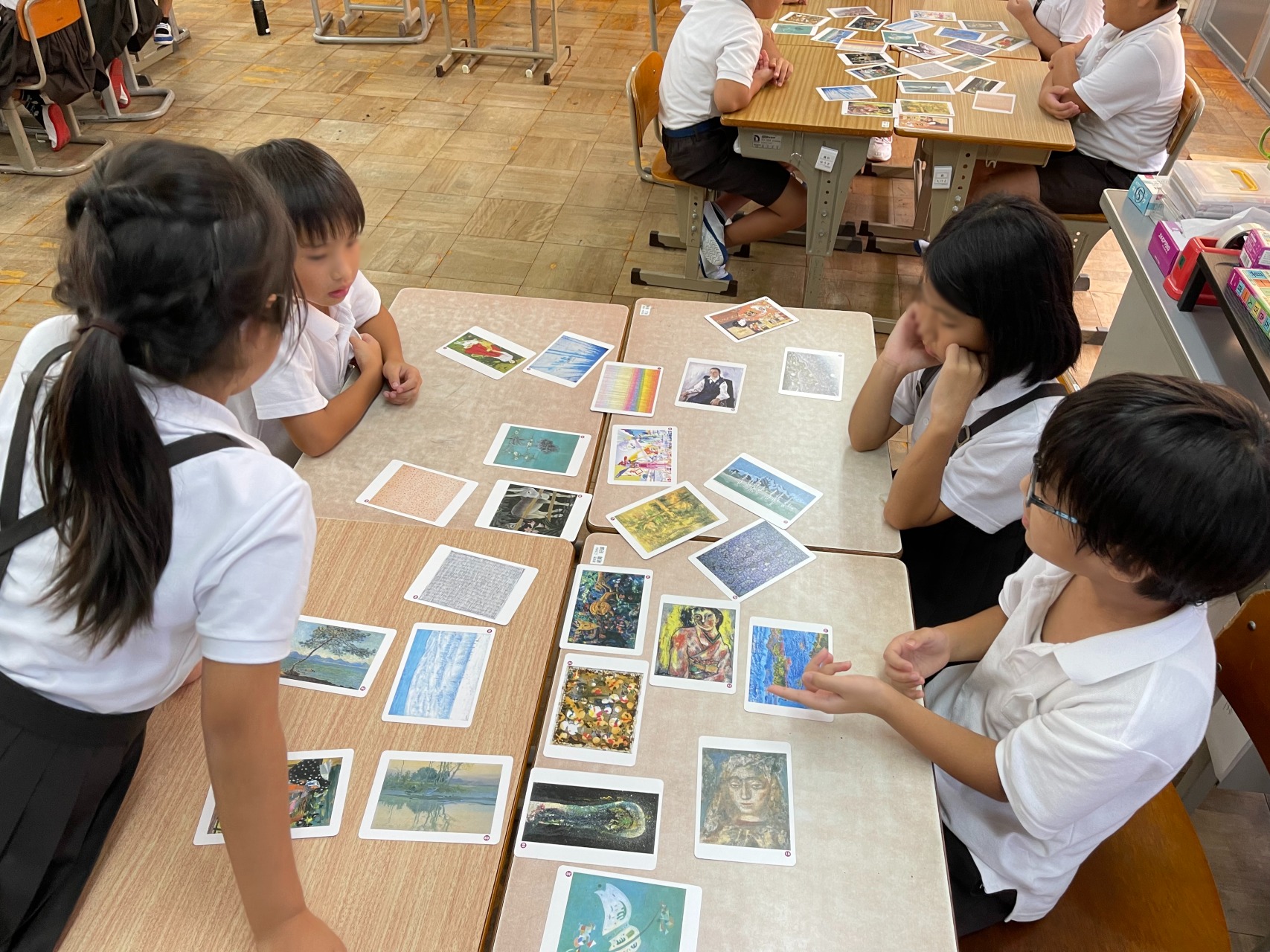 机に並べたアートカードを4人の子供が囲んでゲームをしている様子